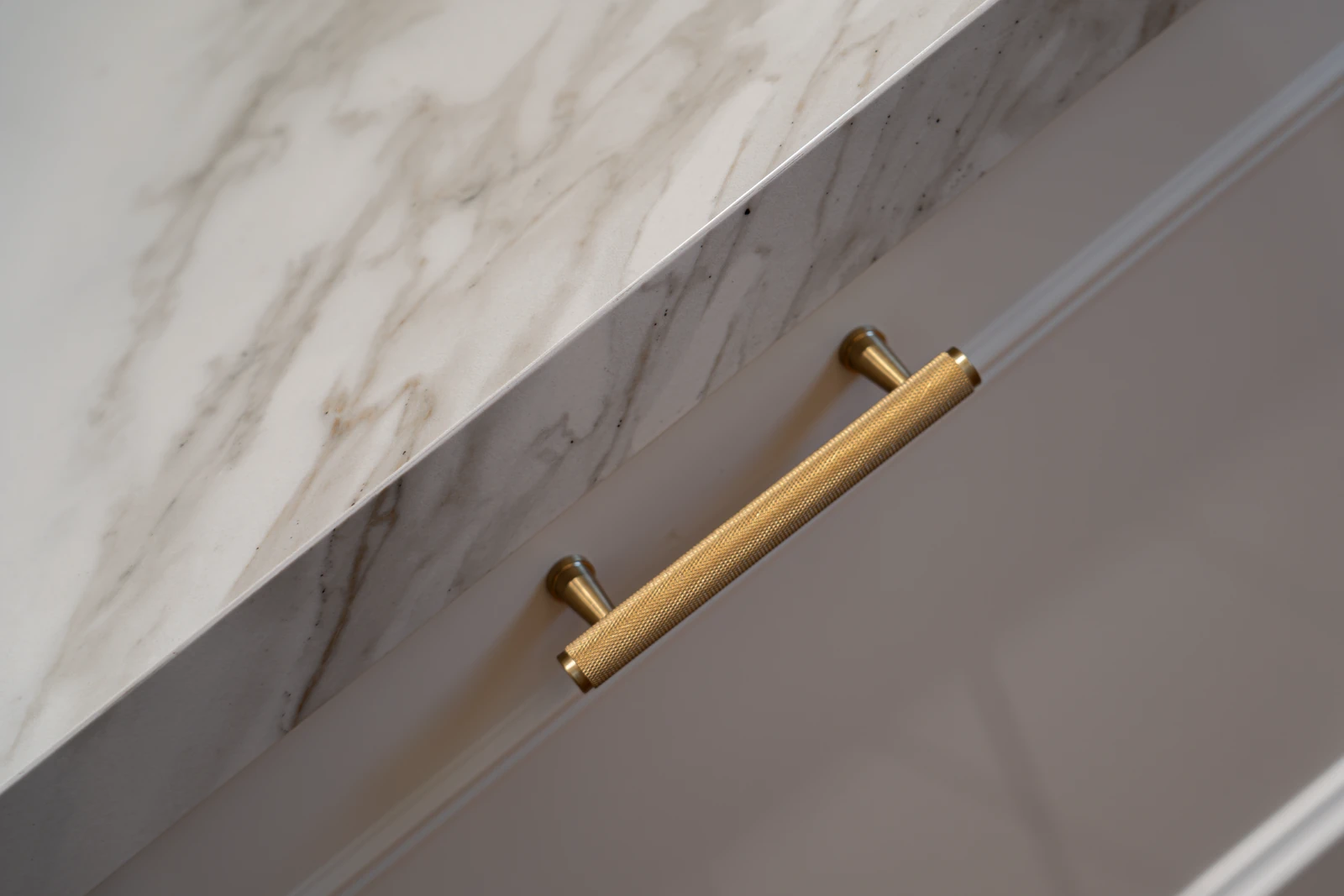 Brass cabinet handle and stone worktop detail in the Karigar kitchen at Deema 1, Villa 55