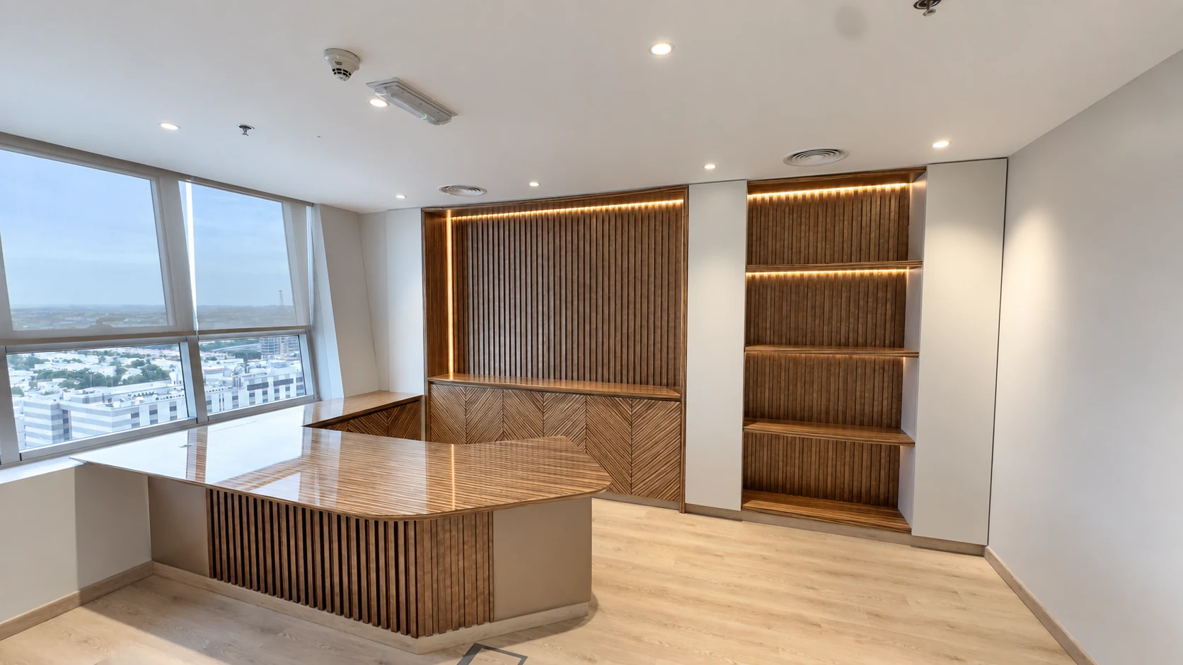 Bespoke curved timber desk with fluted panels, chevron cabinetry and illuminated shelving at Indigo Tower